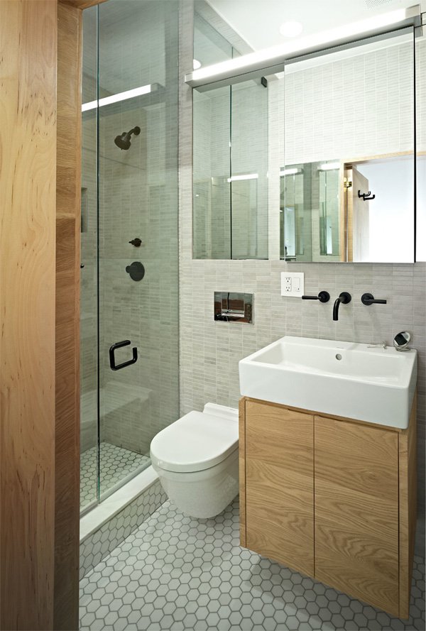 Salle de bains avec grands miroirs, murs et sol gris et meubles en bois naturel. 