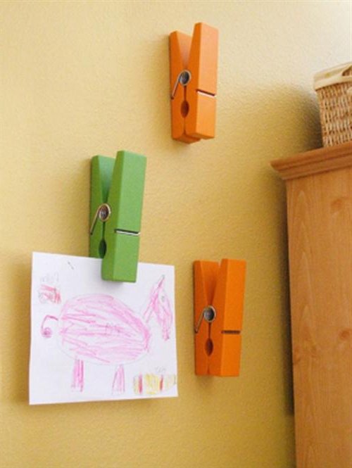 Des pinces à linge sur le mur avec des dessins d'enfants.