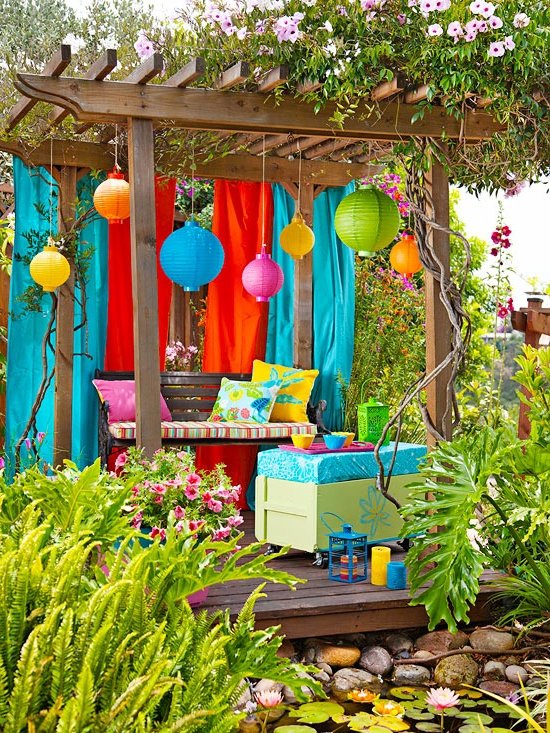 décoration de jardin colorée avec une pergola, des lampes colorées et des bancs avec des coussins