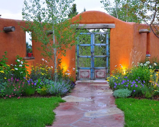Jardin vert avec des murs orange et un portail avec des garde-corps